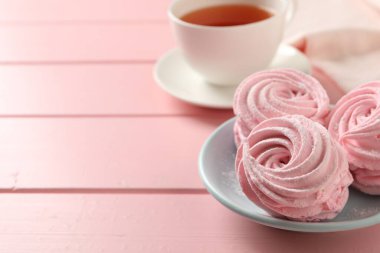 Delicious zephyrs served with tea on pink wooden table, space for text