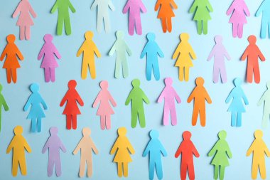Many different paper human figures on light blue background, flat lay. Diversity and inclusion concept