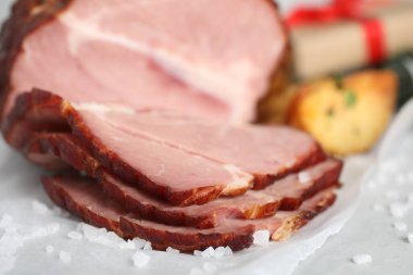 Cut delicious ham with salt on table, closeup