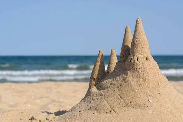 Beach with sand castle near sea on sunny day. Space for text