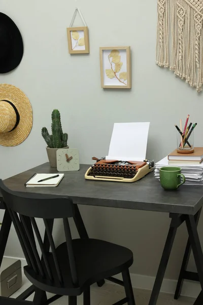 Typewriter and stack of papers on dark table in room. Writer\'s workplace