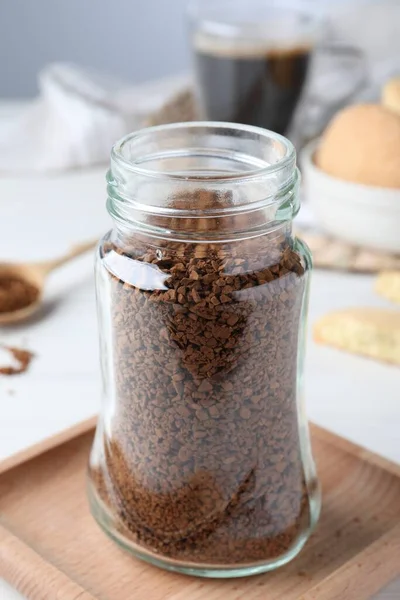 Open jar of instant coffee on white table