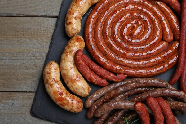 Different delicious sausages on wooden table, top view. Assortment of beer snacks