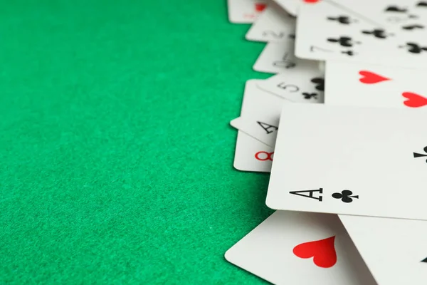 Deck of playing cards on green table, closeup. Space for text