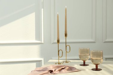 Beyaz masada yanan mumların yanında şarap kadehleri, metin için yer.