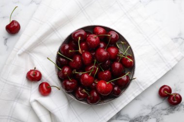 Fresh ripe cherries with water drops on white marble table, flat lay