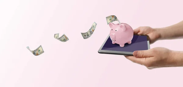 Man Holding Tablet Piggy Bank Flying Dollar Banknotes Pink Background — Stockfoto
