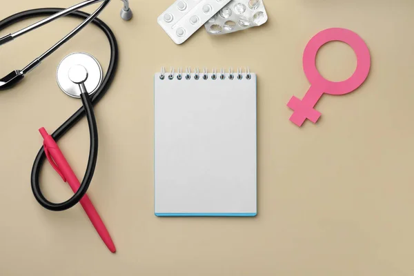 Flat lay composition with female gender sign and stethoscope on beige background. Women\'s Health concept