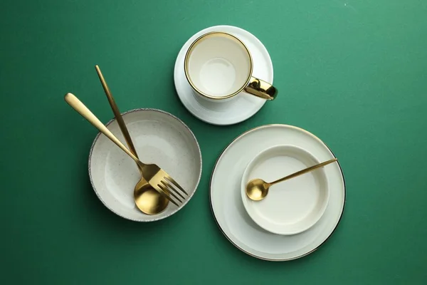 Stylish Empty Dishware Golden Cutlery Green Background Flat Lay — Stockfoto