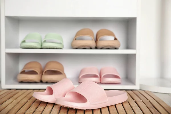 Stylish rubber slippers and storage cabinet with shoes indoors