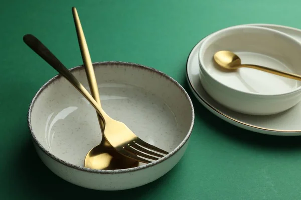 Stylish Empty Dishware Golden Cutlery Green Background — Stockfoto