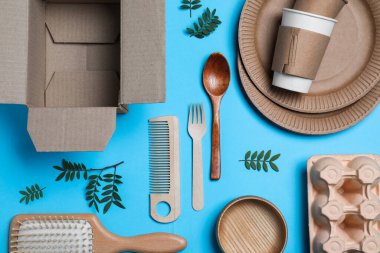 Different eco items on light blue background, flat lay. Recycling concept