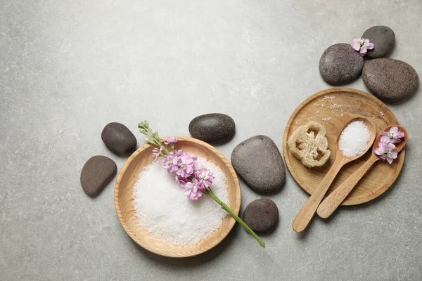 Flat lay composition with sea salt and spa stones on grey marble table