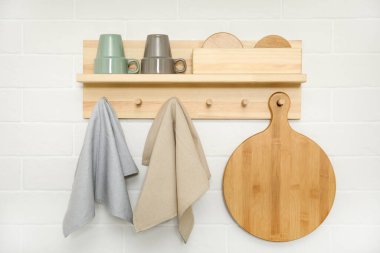 Different towels and wooden board hanging on rack in kitchen