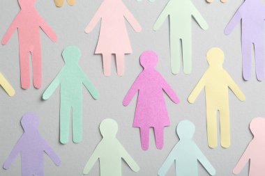 Many different paper human figures on grey background, flat lay. Diversity and inclusion concept