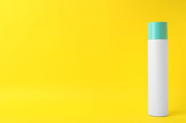 Bottle of dry shampoo on yellow background. Space for text