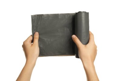 Woman holding roll of grey garbage bags on white background, closeup. Cleaning supplies