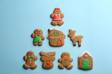 Açık mavi arka planda Noel ağacı şeklinde dizilmiş lezzetli zencefilli kurabiyeler.