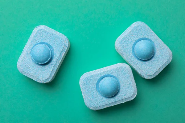 Water softener tablets on turquoise background, flat lay