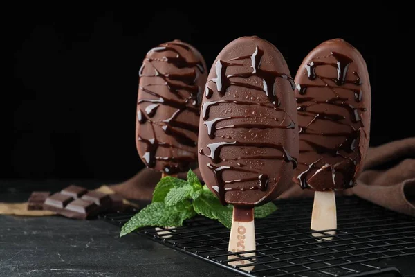 Delicious glazed ice cream bars and mint on black table. Space for text