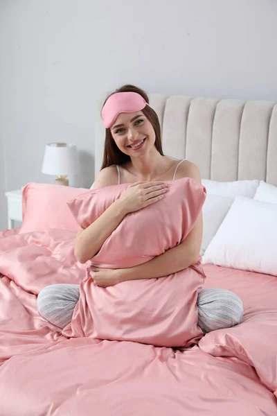 年轻女子抱着枕头躺在柔软的床上 床上铺着丝质的亚麻布 — 图库照片