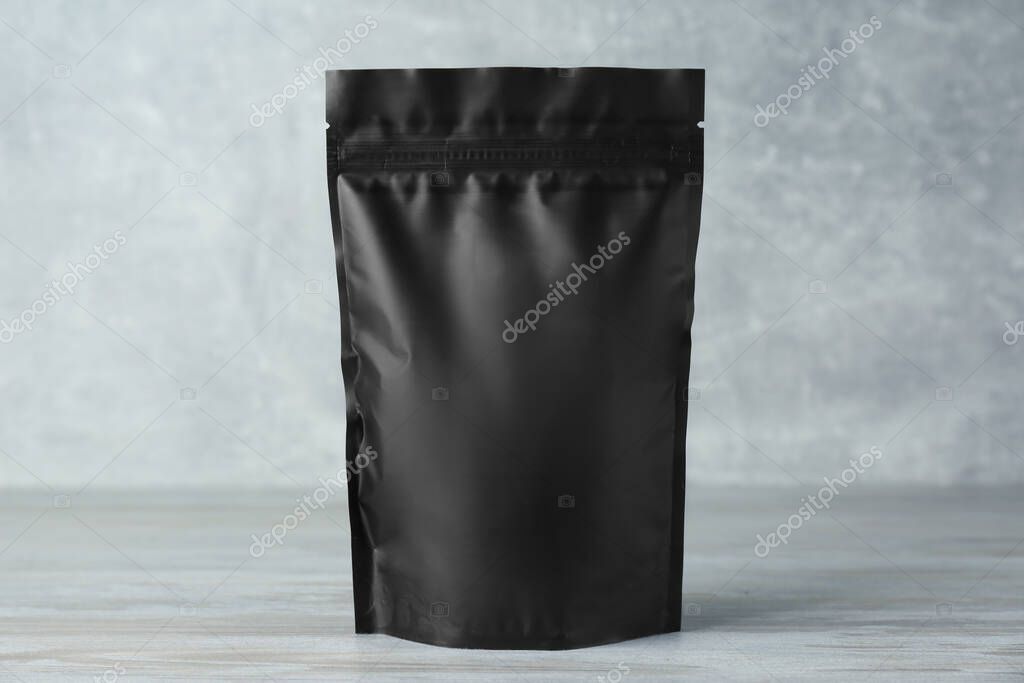One blank foil package on wooden table against light grey background