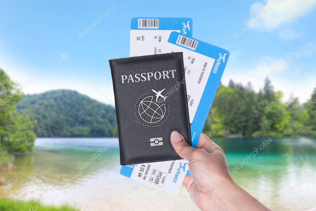 Woman holding passport with boarding passes and beautiful view of river on background