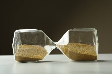 Hourglass with sand on white table. Menopause concept