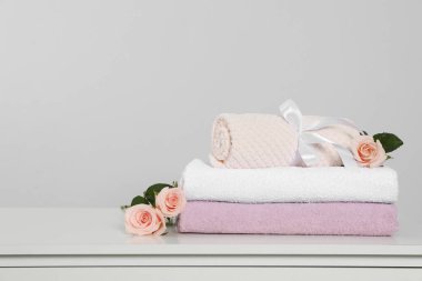 Clean soft towels with flowers on white table against light grey background. Space for text
