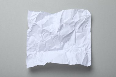 Gri arkaplan üzerine beyaz buruşuk kağıt yaprağı, üst görünüm