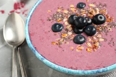 Gri masada servis edilen granola ve chia tohumlu lezzetli acai smoothie.