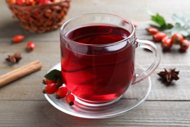 Aromatik gül kalça çayı ve taze böğürtlenler ahşap masada, yakın plan.