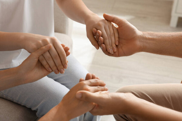 Group of religious people holding hands and praying together indoors, closeup