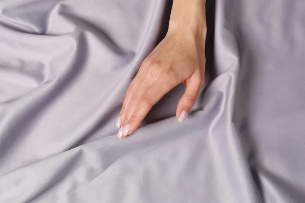 Woman touching soft silver fabric, top view