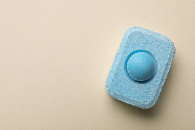 Water softener tablet on beige background, top view. Space for text