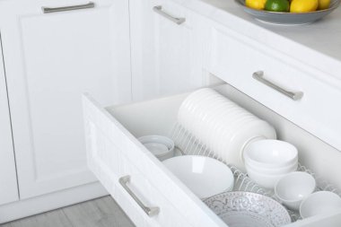 Open drawer with different plates and bowls in kitchen