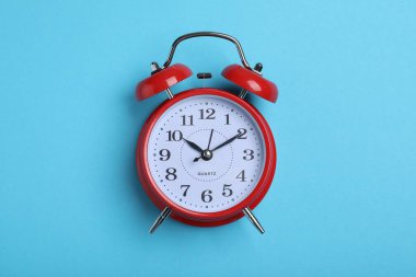 Açık mavi arkaplandaki alarm saati, üst görüntü. Okul zamanı.