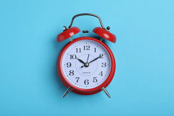 stock image Alarm clock on light blue background, top view. School time