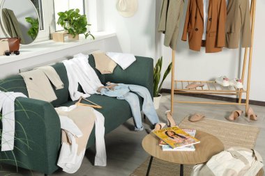 Kanepede kirli giysiler ve oturma odasında ayakkabılar.