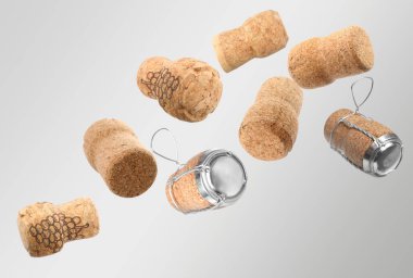 Many corks of sparkling wine bottles falling on light grey background