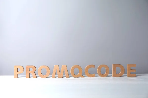 Words Promo Code made of wooden letters on white table, space for text