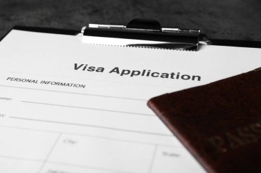 Visa application form for immigration and passport on grey table, closeup