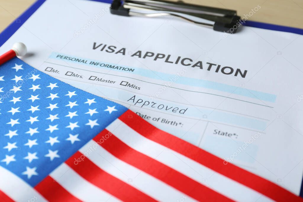 Visa application form for immigration and American flag on table, closeup