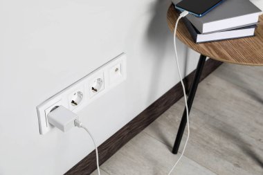 Modern smartphone charging from electric socket indoors
