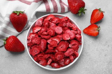 Freeze dried and fresh strawberries on light grey table, flat lay