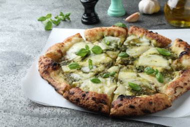 Delicious pizza with pesto, cheese and basil on grey table