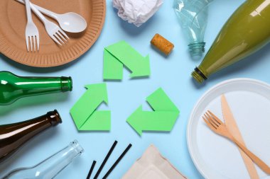 Recycling symbol, glass and plastic items on light blue background, flat lay