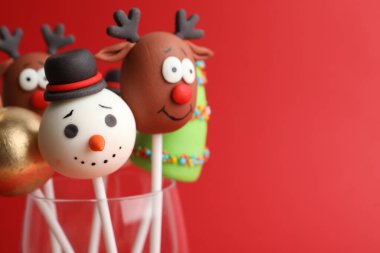 Delicious Christmas themed cake pops on red background, closeup. Space for text