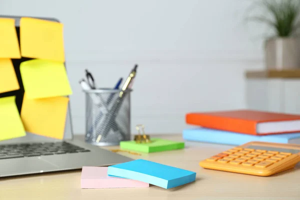Colorful sticky notes, laptop and stationery on wooden table