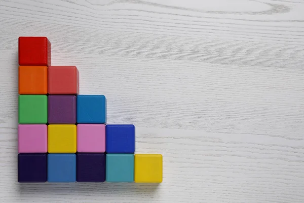 Many colorful cubes on white wooden background, flat lay with space for text. Management concept